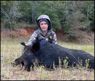A picture of Justin Miller with his trophy boar hog taken at TEN26 Outdoors hunting service