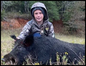 A picture of Justin Miller with his trophy boar hog taken at TEN26 Outdoors hunting service
