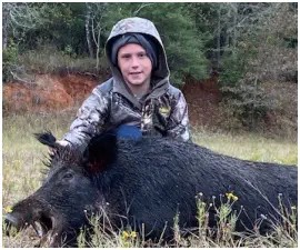 A picture of Justin Miller with his trophy boar hog taken at TEN26 Outdoors hunting service